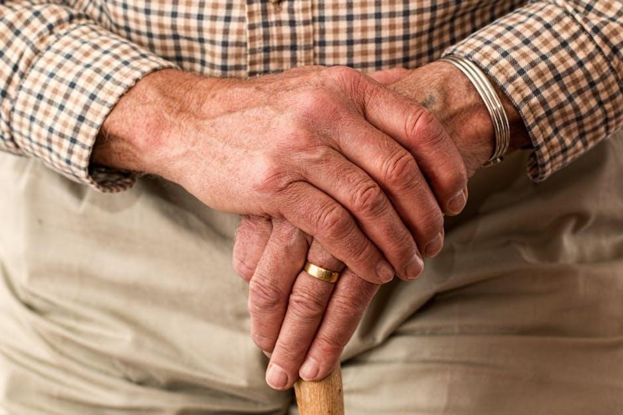 Mi_preoccupo_solo_dellet_in_relazione_alla_mia_salute_RY085cmjQ8 - Confidenze24 Source: Pixabay - pexels - A detailed image of elderly hands clasping a wooden cane, symbolizing aging and support.