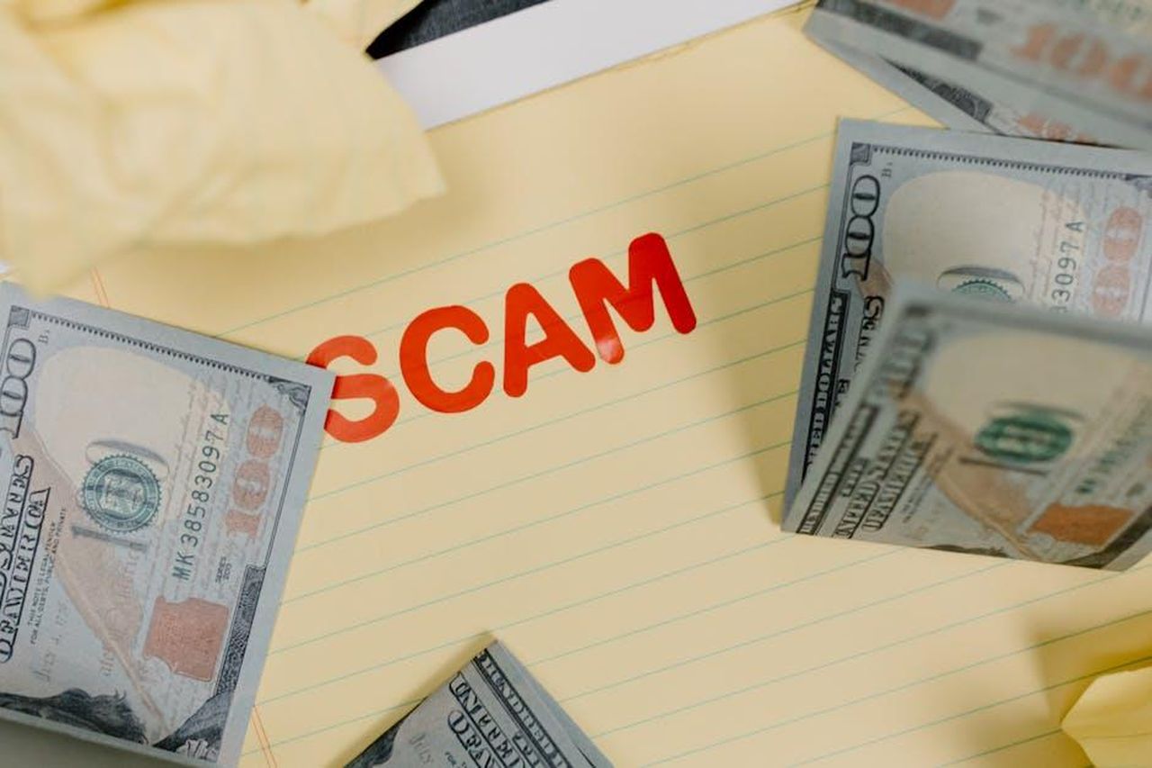 Minacce_legali_per_un_colloquio_AydhwON9K5 - Confidenze24 Source: Tara Winstead - pexels - Conceptual image of financial scam with US dollars on yellow paper and word 'scam' visible.