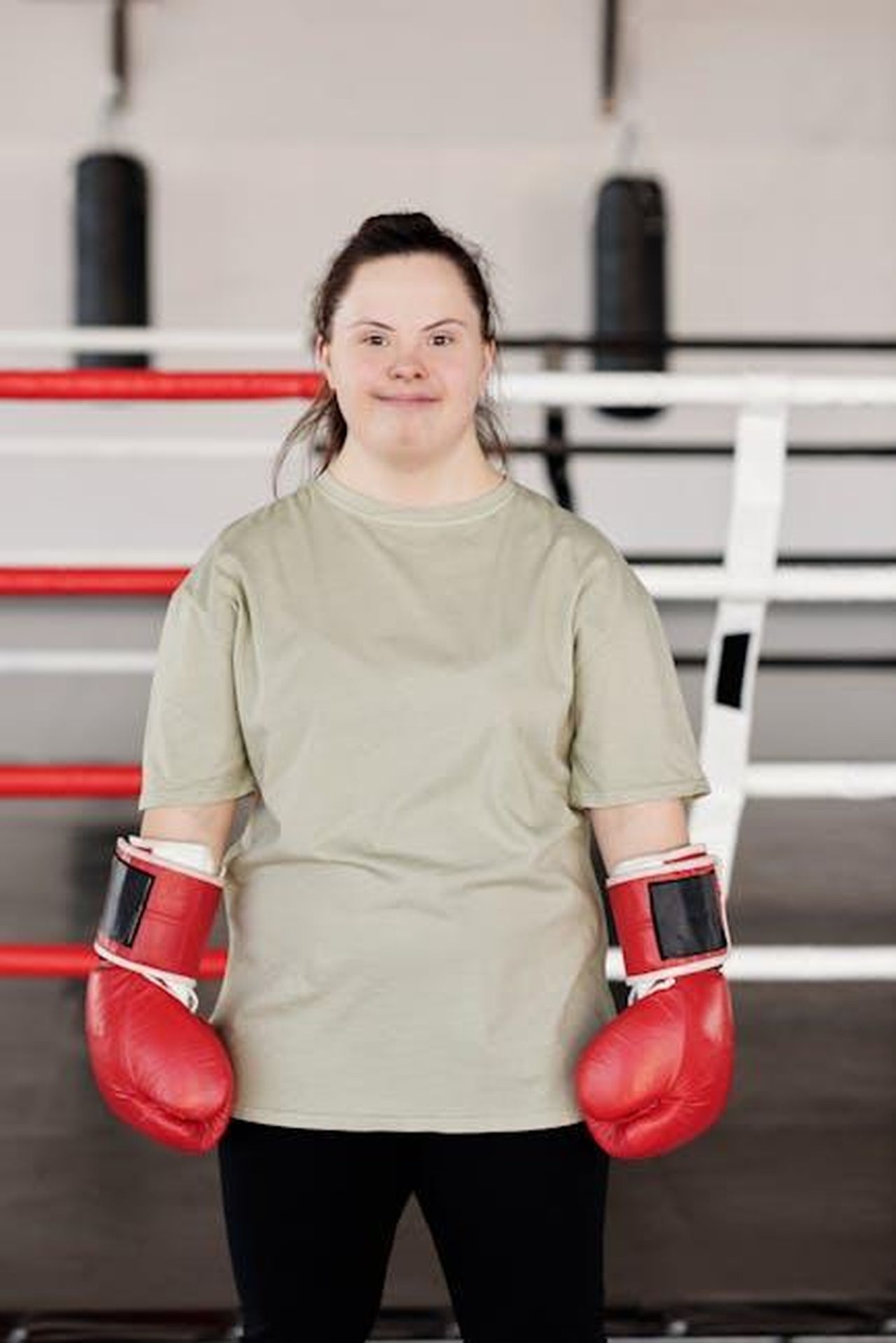 Richiedere_formazione_inclusiva_LGBTQIA_a_scuola_3qRzibO2DJ - Confidenze24 Source: Cliff Booth - pexels - Woman with Down syndrome confidently posing in boxing gloves inside a modern gym.