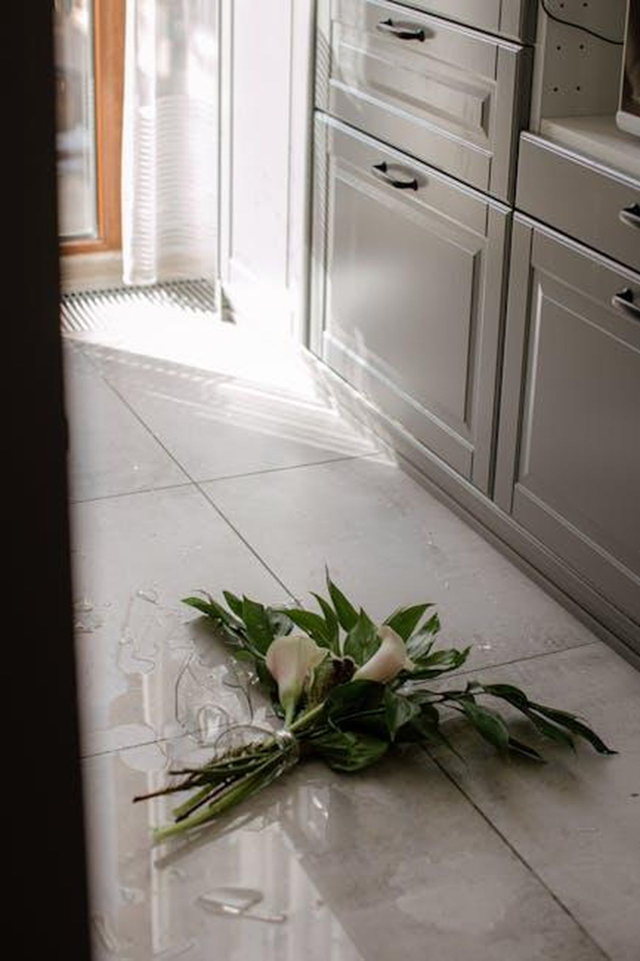 Riflessioni_sul_divorzio_e_la_convivenza_SVSga1Yf2w - Confidenze24 Source: Anastasia Shuraeva - pexels - A bouquet and shattered glass on a kitchen floor, sunlit through a window, conveys unexpected mishap.