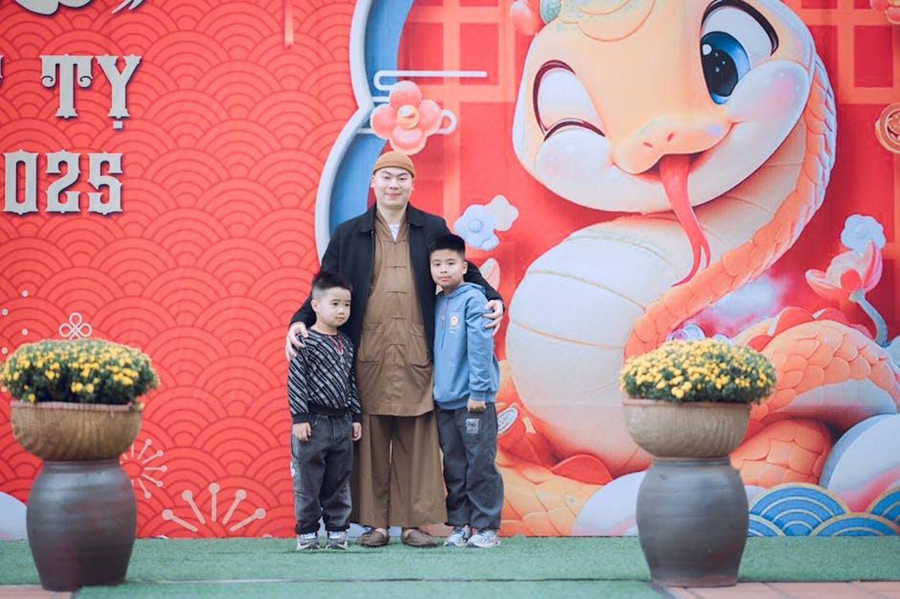 Rumor_su_altri_partecipanti_a_CBB_2025_5CL1wkKUCJ - Confidenze24 Source: Tuấn Kiệt Jr. - pexels - A family poses with a festive New Year snake mural, welcoming 2025 with joy.