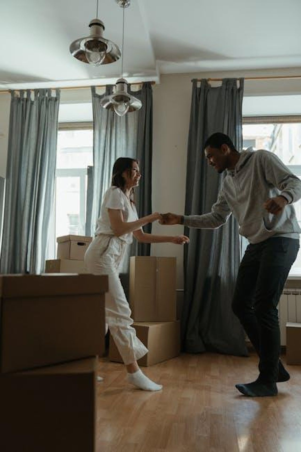 Source: cottonbro studio - pexels - Happy couple dancing among cardboard boxes in their new home, celebrating a fresh start.