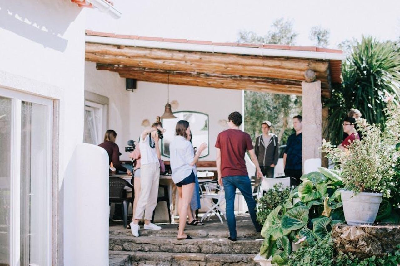 Sue_Devaney_parla_della_trama_9Qx1KGwFTZ - Confidenze24 Source: Lisa from Pexels - pexels - A group of young adults socializing outdoors on a sunny patio, surrounded by greenery.