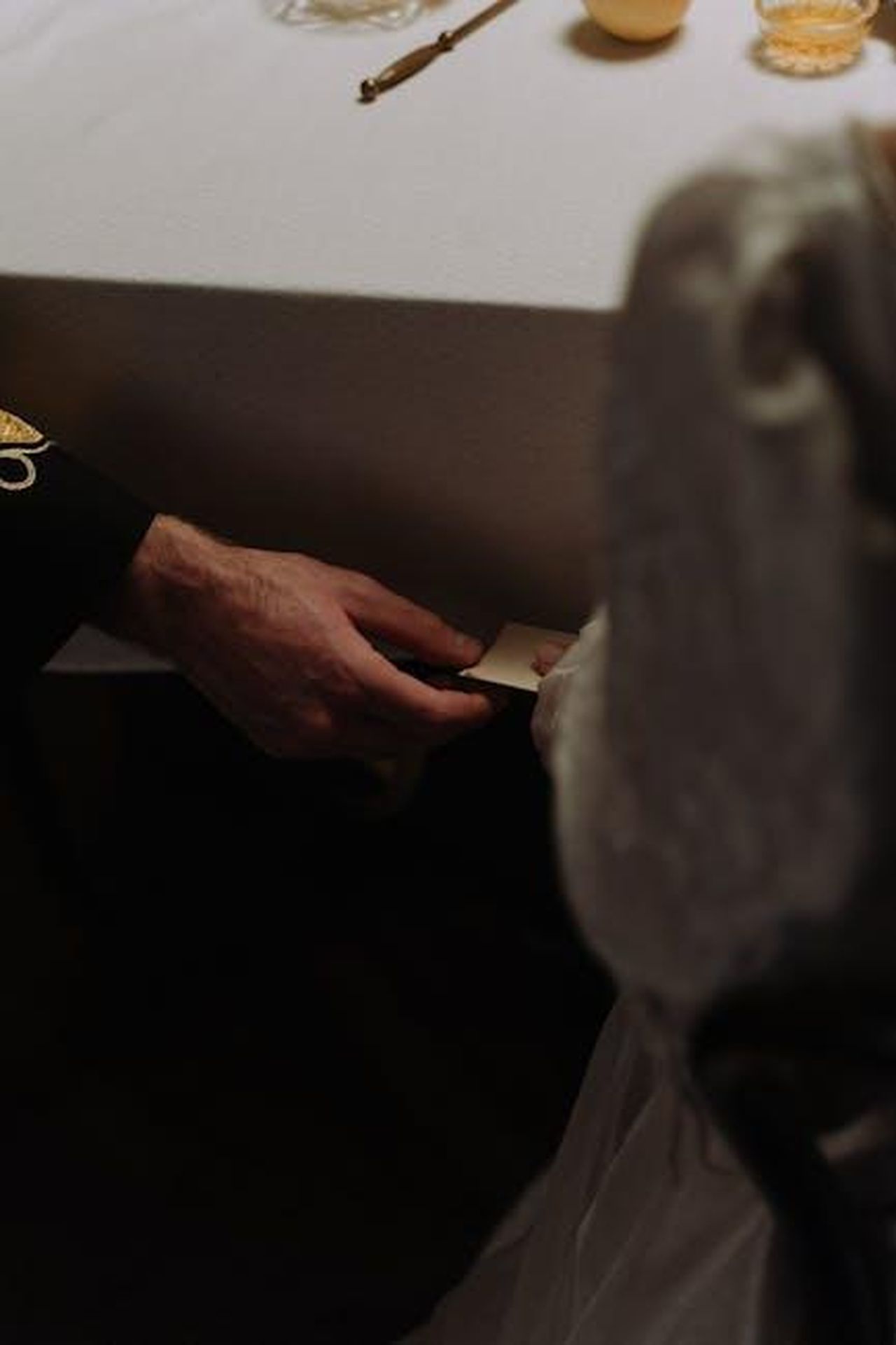 Source: cottonbro studio - pexels - A romantic moment with a note exchanged below a dining table.